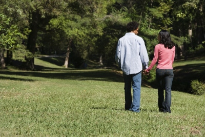 Couple holding hands walking and talking in park