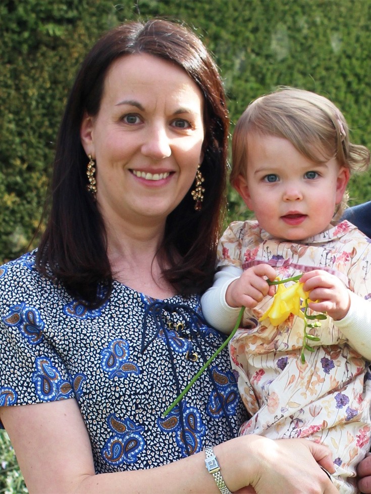 strong smart woman smiling with her adorable baby holding a yellow flower