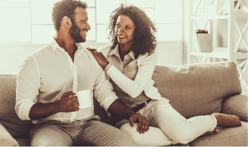 Love U success story of beautiful couple wearing all white on couch staring at each other's eyes