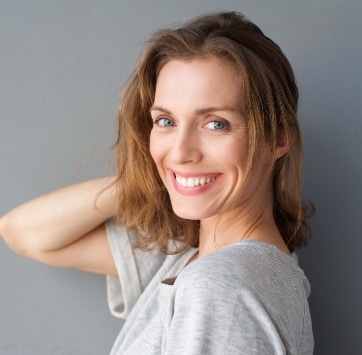 woman with grey eyes holding her hair back up, wearing light grey shirt