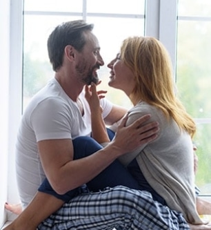 sweet couple sitting next to a window, cuddling