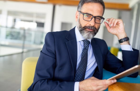 bearded businessman wearing eyeglasses while holding a file