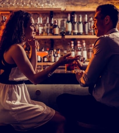 man and woman chatting while drinking at a bar