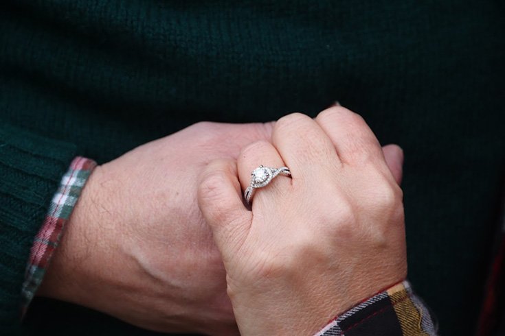 a man holding her woman's hand with an engagement ring