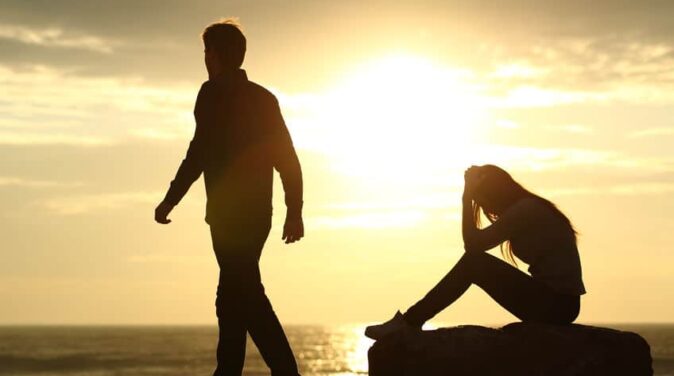 Couple silhouette breaking up a relation on the beach at sunset