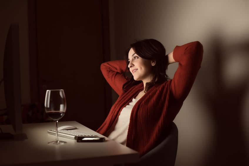 attractive beautiful woman wearing red sweaters sitting and drinking wine while dating online